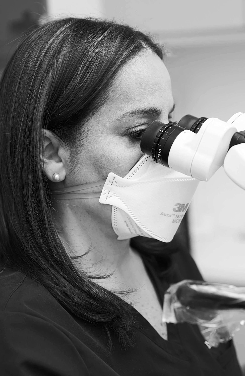 Person using a microscope while wearing a mask.