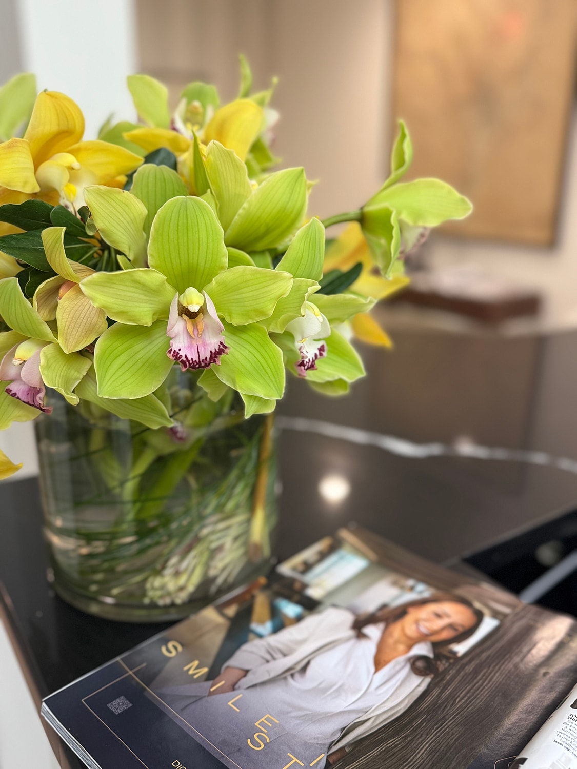 Vibrant orchids in glass vase on table.